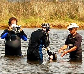Randy video tapes Della locating targets using an underwater metal detector with Ray's help.
