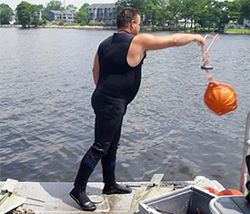Jeremy throws a buoy into the water to mark the location of side scan sonar contact to be checked out.
