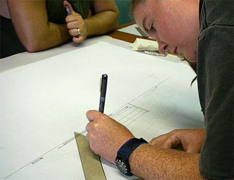 Mel inks the drawing.
