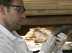Brennan Bajdek examining and cleaning lead artifact.