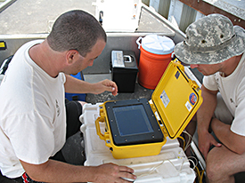 Tim Holmes and Gary MacMullen observe the side scan sonar screen during their day of 	survey.